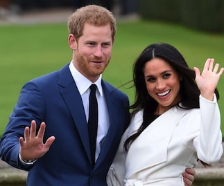 A happy Prince Harry with Meghan Markle on his arm in front of a long lawn